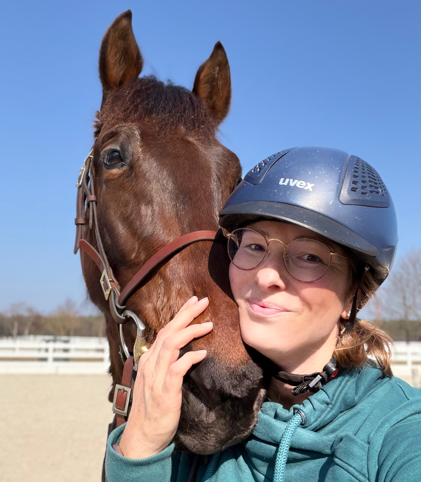 Kathi Stec mit ihrem Pferd, beide lächeln in die Kamera, an einem sonnigen Tag.